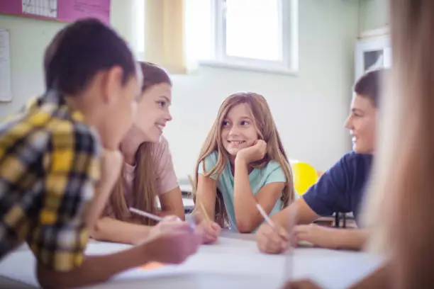 With friends everything is easy. Teenagers students sitting in the classroom and talking.