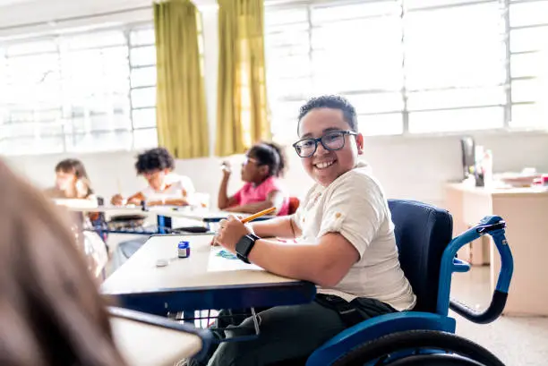 Portrait of a wheelchair student painting on classroom at school